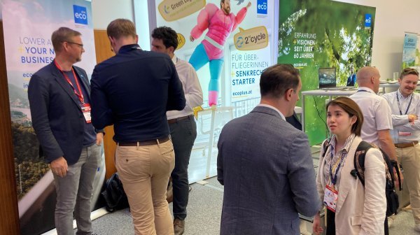 Mehrere Personen reden beim Connect Day 2025 bei einem Messestand miteinander. Im Hintergrund sind Rollups zu sehen.