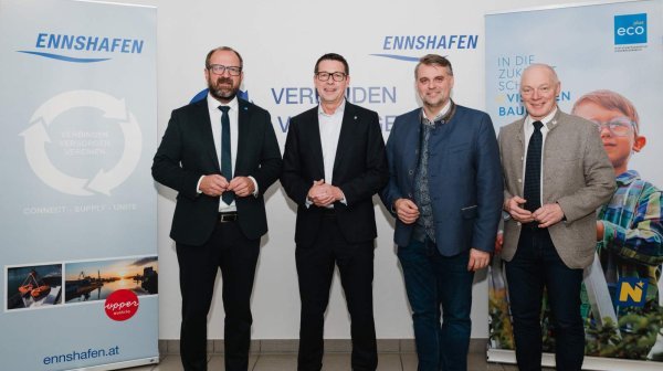 Vier Personen in formeller Kleidung stehen vor zwei Roll-ups.