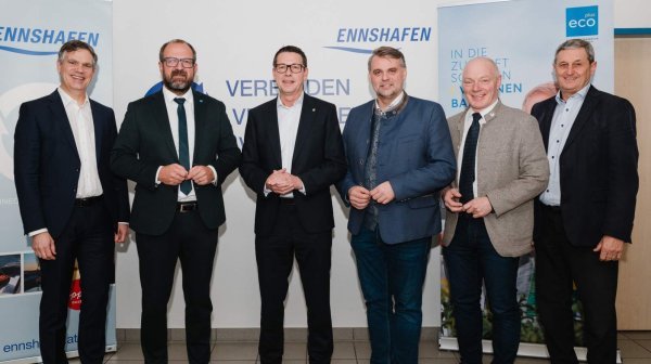 Sechs Personen in formeller Kleidung stehen nebeneinander vor zwei Roll-ups