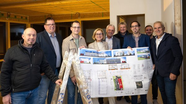 Personengruppe mit Leiter und Erweiterungsplan in einem Firmenrohbau 