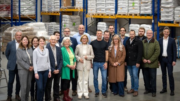 Große Personengruppe in einem mit Säcken gefüllten Hochreegallager