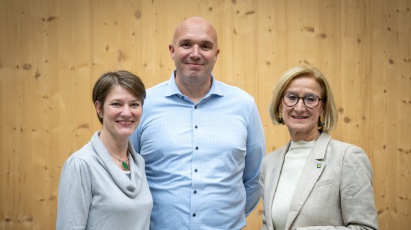 Drei Personen stehen vor einer Holzwand – Medibox Schrems