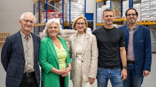 Fünf Personen stehen in einem vollen Hochregal-Lager