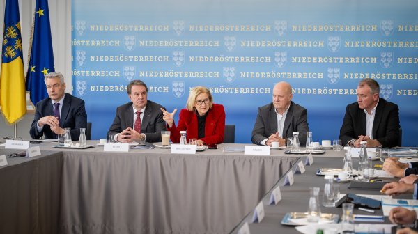 Fünf Personen sitzen bei einer Diskussionsrunde vor Fahnen und einer Niederösterreich-RückwandPressekonferenz 