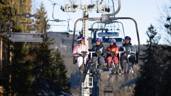 Vier Skifahrer sitzen auf Sessellift in Lackenhof