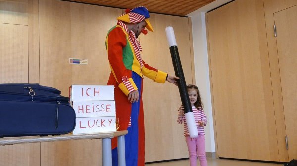 Großer verkleideter Clown Lucky mit extragroßen Zauberstab und Kindergartenkind