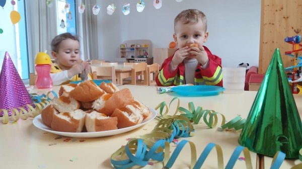 Zwei Kindergartenkinder beim Hineinbeissen in Krapfen