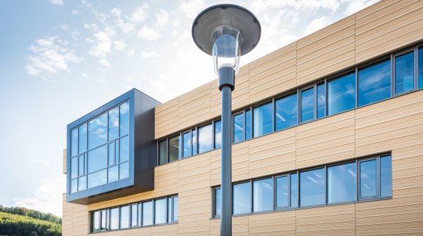 Teil eines Gebäudes mit Holzfassade und einigen Fenstern mit dunklem Rahmen in einer Reihe mit einer Straßenlaterne im Vordergrund