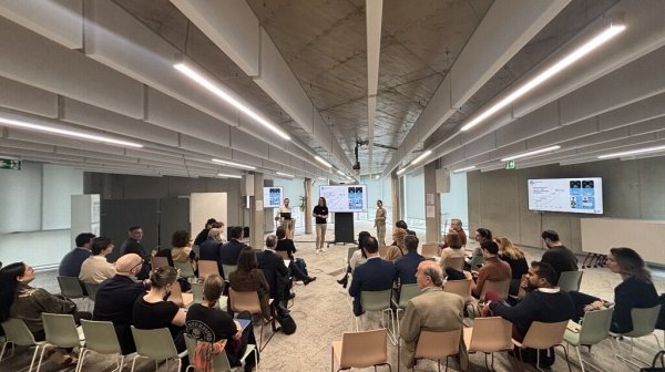 Veranstaltung, Raum mit Stühlen und einer Bühne und einigen Personen, die auf den Stühlen sitzen