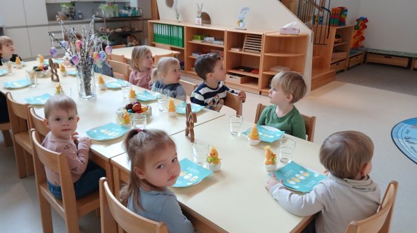 Kindergartenkinder sitzen um einen österlich gedeckten Tisch