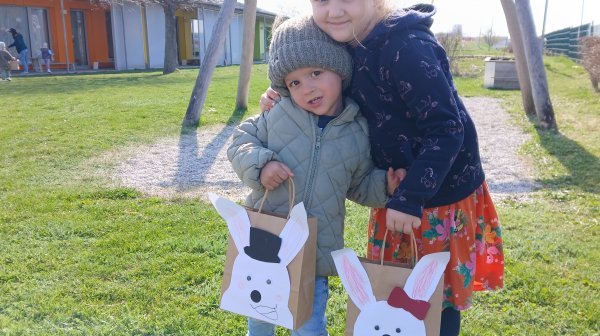 Zwei Kindergartenkinder im Garten mit Ostersackerl in der Hand 