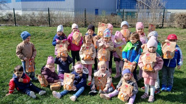 Eine Gruppe an Kindergartenkindern mit Ostersackerl steht im Garten 