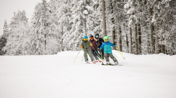 Kindergruppe beim Skifahren auf winterlicher Piste
