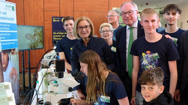 Einige Erwachsene mit Gruppe an Jugendlichen bei Forschungsstation