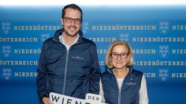 Ein Mann und eine Frau stehen vor einer blauen Wand.