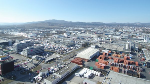 Luftbild großer Wirtschaftspark mit hochrangigen Straßen, Containerlager und sanften Bergen im Hintergrund