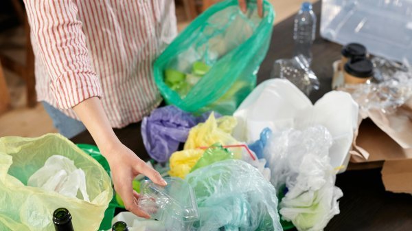 Person sortiert Plastikabfälle wie Flaschen und Verpackungen auf einem Tisch