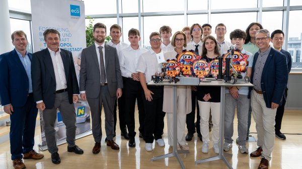 Gruppenfoto mit Teilnehmenden einer Robotikveranstaltung, mehreren Robotermodellen und Auszeichnungen.