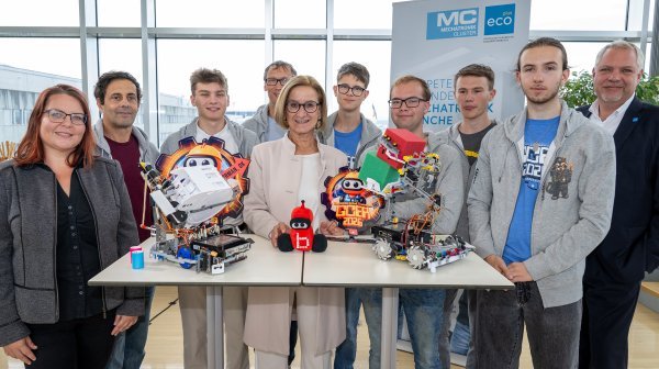 Gruppenfoto mit Teilnehmenden einer Robotikveranstaltung, mehreren Robotermodellen und Auszeichnungen.