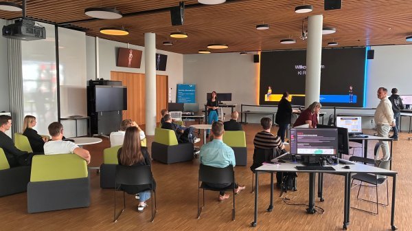 Teilnehmende einer Informationsveranstaltung im KI Reallabor verfolgen eine Präsentation in einem modernen Schulungs- und Demonstrationsraum.