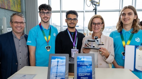 Gruppenfoto mit Teilnehmenden einer Robotikveranstaltung, mehreren Robotermodellen und Auszeichnungen.
