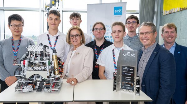 Gruppenfoto mit Teilnehmenden einer Robotikveranstaltung, mehreren Robotermodellen und Auszeichnungen.