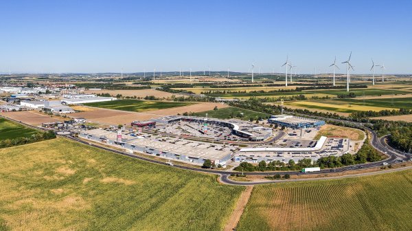 Drohnenansicht Fachmarktzentrum und Wirtschaftspark Bruck an der Leitha mit Windrädern am Hoizont