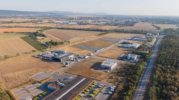 Drohnenansicht auf ein Wirtschaftsparkarel mit BUndestraße 54, vielen Feld- und Wandflächen und der Stadt Wiener Neustadt im Hintergrund