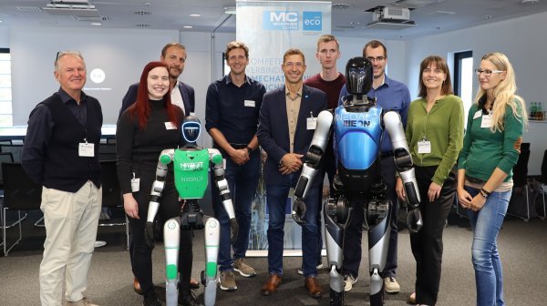 Gruppenfoto der Teilnehmenden einer Veranstaltung mit zwei humanoiden Robotern.