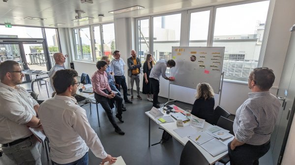 Projekt Kick-off UP!crete wo einige Personen rund um Flip-Chart stehen