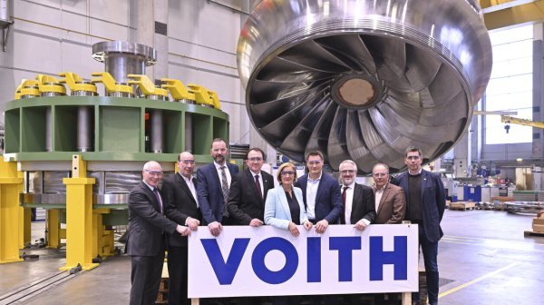 Gruppenfoto bei VOITH vor einer riesigen Turbine