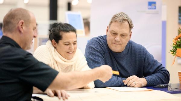 Drei Personen sprechen über einen Bauplan