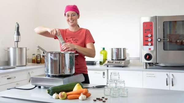 Frau bei der Gemüseverarbeitung in einer Großküche