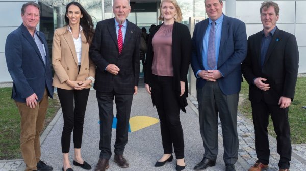 Sechs Personen stehen nebeneinander vor Gebäudeeingang