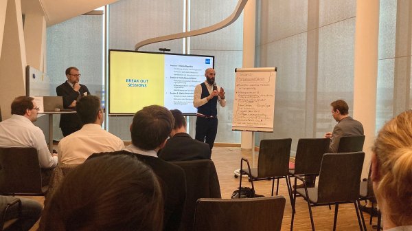 Vortragsraum mit vortragenden Personen und Publikum