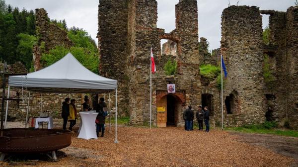 Ruinenansicht mit kleinem weißen Zelt und mehreren Personen 