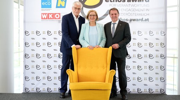 3 Personen stehen hinter gelben Sessel bei ethos award 2024 Aufruf