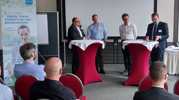 Personen bei Stehtischen sprechen vor Publikum