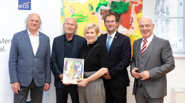 Vier Männer und eine Frau stehen vor Gemälde und halten Katalog in Händen