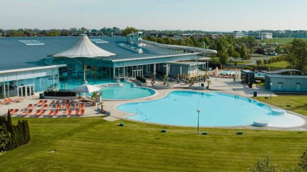 Ein Gebäudekomplex mit einem Pool im Vordergrund und einer grünen Wiese 