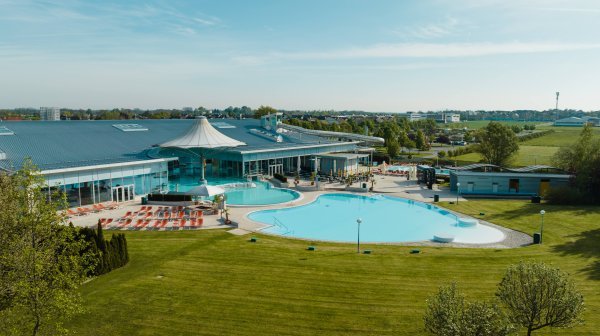 Ein Gebäudekomplex mit einem Pool im Vordergrund und einer grünen Wiese 