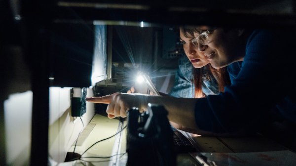 LNF Michael Meindl 2024 05 24 0249 Sehr dunkles Bild mit zwei Frauenprofilen und einem Lichtkegel auf ein Gerät