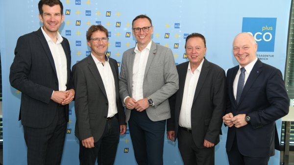 5 Männer stehen vor einer ecoplus Rückwand vor der Kamera