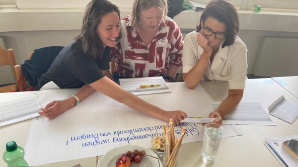 Drei Personen gestalten Plakat