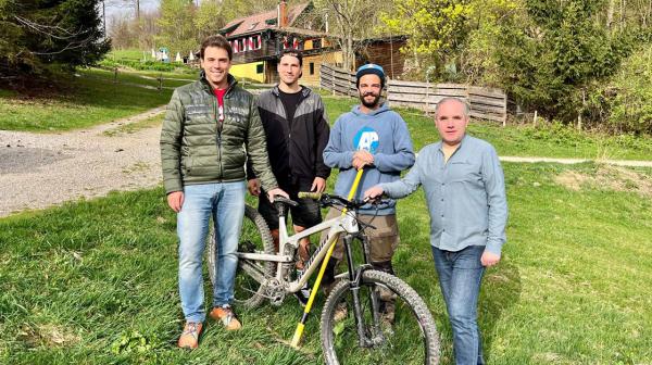 4 Herren stehen mit MTB auf einer Wiese vor einer Berghütte