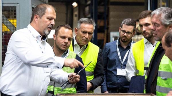 Person zeigt anderen Personen einen Gegenstand