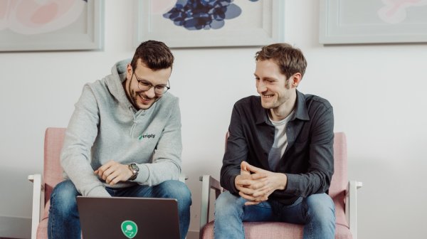 zwei Personen sitzen auf Sesseln und davor steht ein Laptop wo beide hinschauen