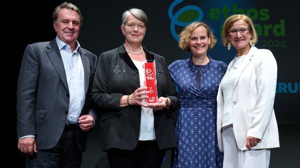 Vier Leute stehen in einer Reihe und halten einen Award