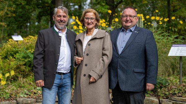 drei Personen stehen nebeneinander und lachen in die Kamera