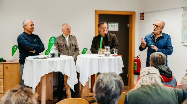 vier Personen stehen nebeneinander und halten ein Mikrofon 